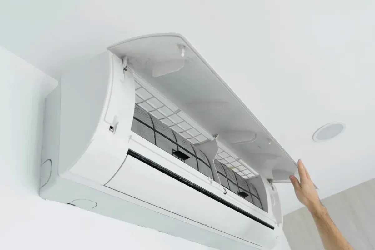 Hand opening the cover of a wall-mounted ductless air conditioner