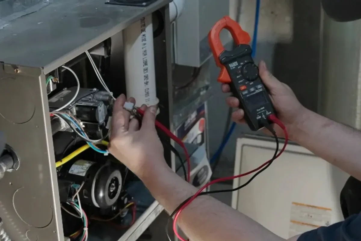 Technician testing a furnace's wiring with a clamp meter